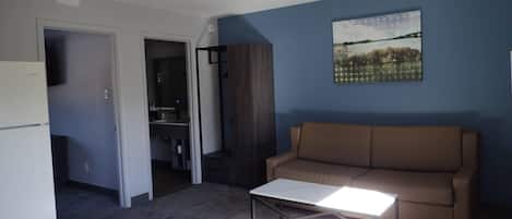 A modern living room with a sofa, a coffee table, and a painting on the wall.
