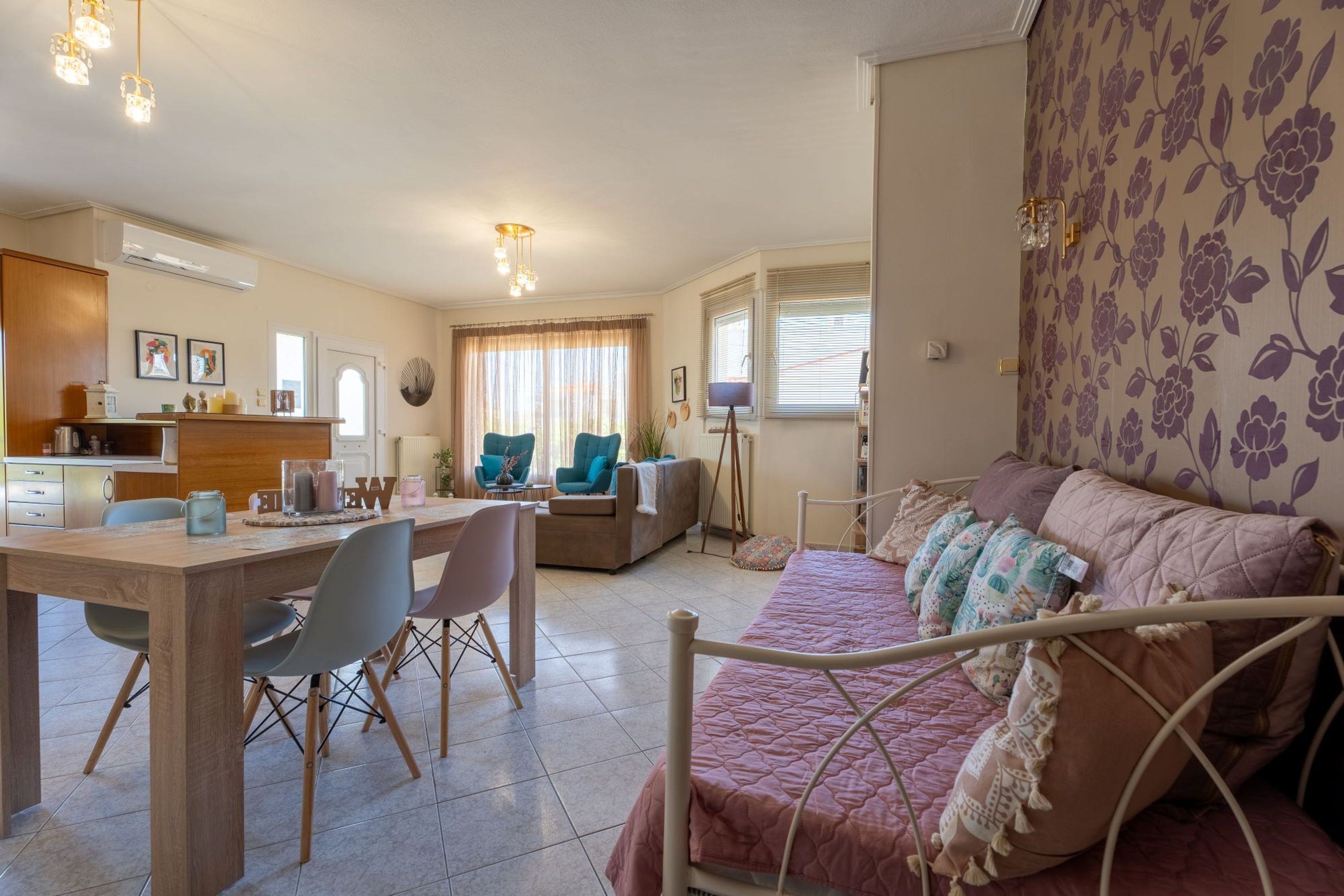 Ein gemütliches Wohnzimmer mit einem Bett, einer Essecke mit Stühlen und einer Küche im Hintergrund.