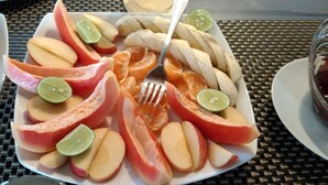 Een bord met gesneden fruit en een vork op een tafel.