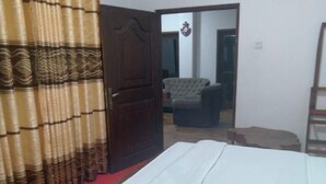 Een slaapkamer met een houten bed, een rode vloerbedekking, een houten deur en een stoel op de achtergrond.