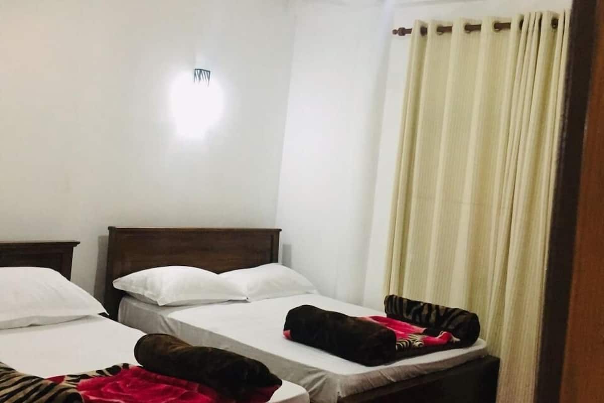 A hotel room with two single beds, a red carpet, and a ceiling light.