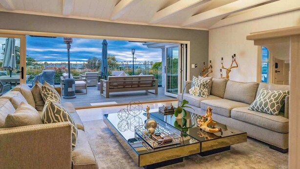 A modern living room with a glass coffee table, a sofa, and a view of the outdoors. - Luxury Home with Pool/Spa/Sauna,Steps to the Beach (San Diego)