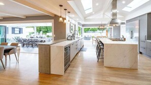A modern kitchen with a central island, dining area, and large windows. - Luxury Home with Pool/Spa/Sauna,Steps to the Beach (San Diego)