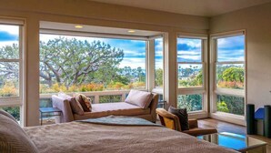 A bedroom with a large window, a bed, a sofa, and a view of trees and hills. - Luxury Home with Pool/Spa/Sauna,Steps to the Beach (San Diego)