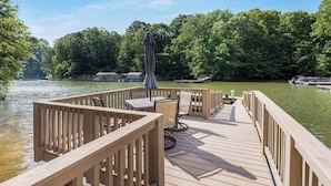Terraza de madera con mobiliario exterior y vista a un lago.