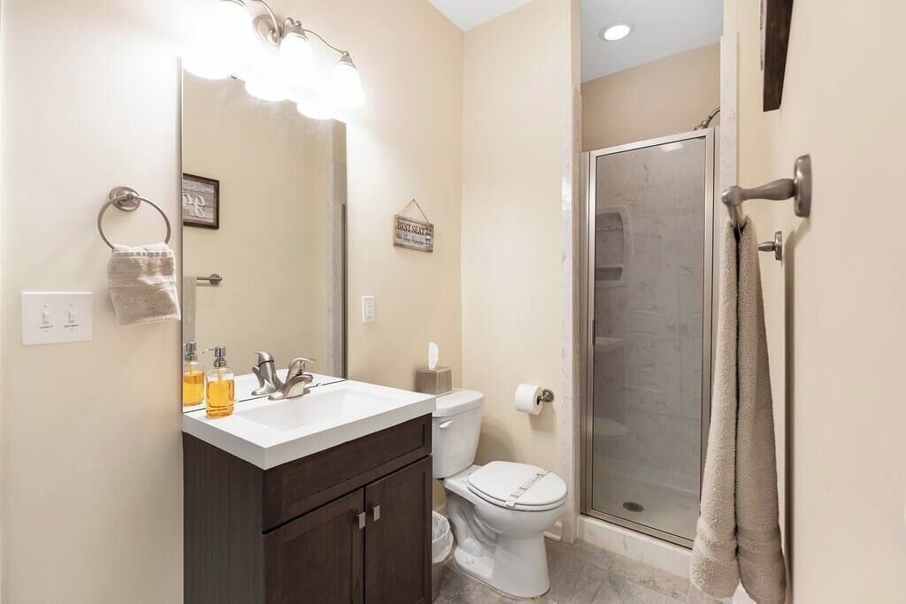 A bathroom with a white sink, dark wooden cabinets, a white toilet, and a glass shower enclosure.