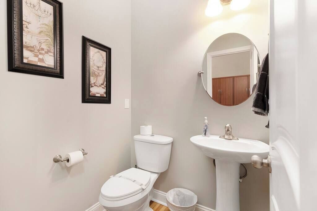 Een badkamer met toilet, wastafel en twee foto's in lijsten aan de muur.