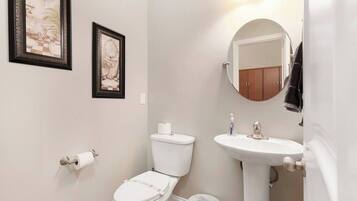 Een badkamer met toilet, wastafel en twee foto's in lijsten aan de muur.