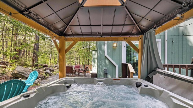 A hot tub area with a covered roof, surrounded by outdoor furniture and a wooden deck.