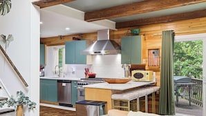 A kitchen with wooden beams, a stove, and a sink.