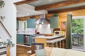 A kitchen with wooden beams, a stove, and a sink.