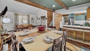 A dining area with a wooden table set for four, a red pot, and a cozy seating arrangement.