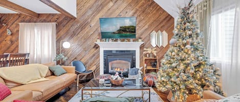 A cozy living room with a fireplace, a Christmas tree, and a comfortable seating area.