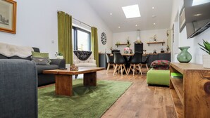 A modern living room with a sofa, a coffee table, and a dining area with chairs and a table. - The Goose Shed (Canterbury)