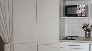 Eine kleine Küche mit weißen Schränken, einer Mikrowelle und einer Arbeitsplatte.