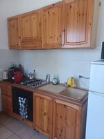 Una cocina con gabinetes de madera, una estufa a gas, un lavabo y un refrigerador blanco.