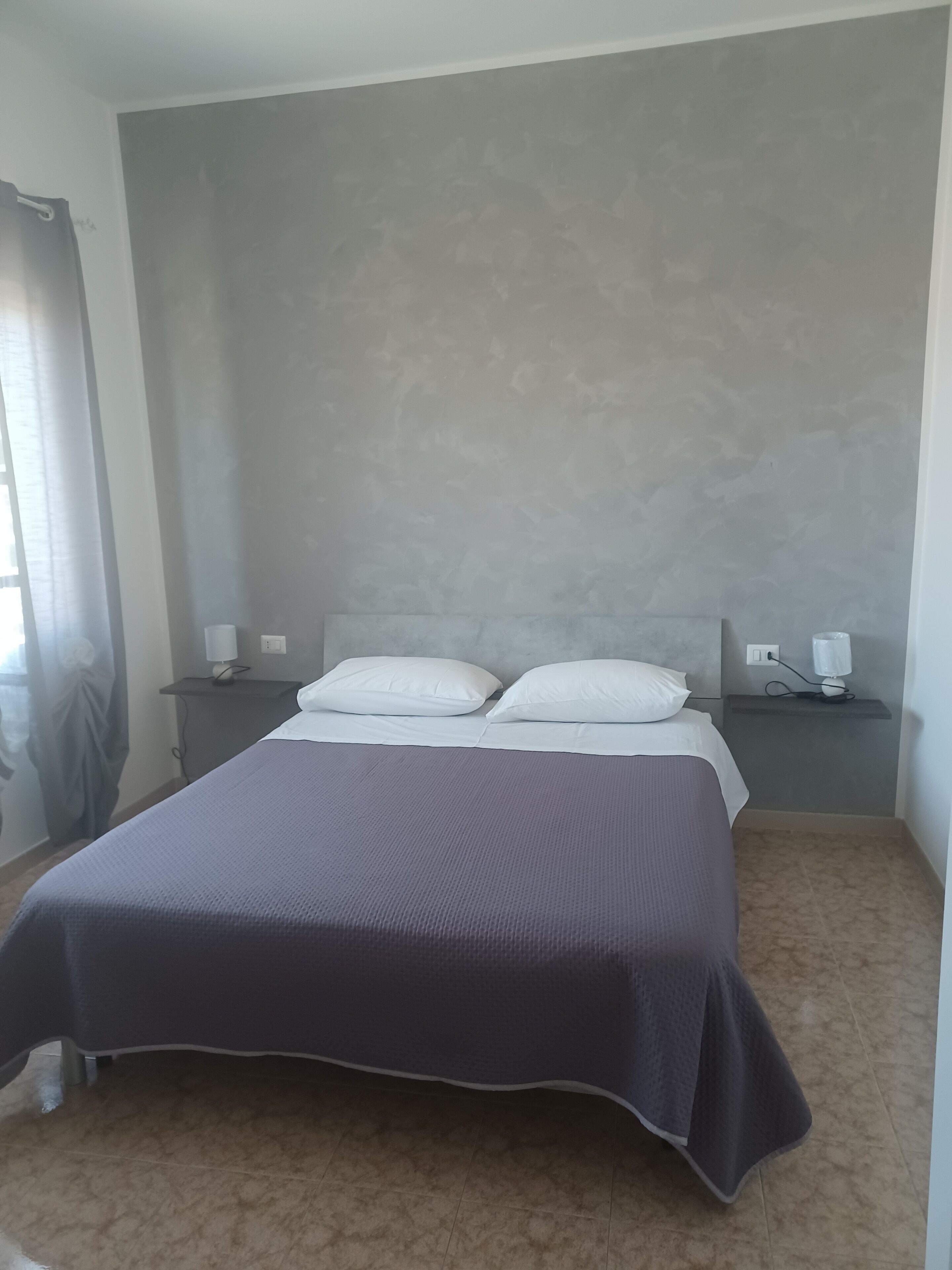 Un dormitorio con una cama, dos mesitas de noche y un pequeño tocador.