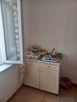 Una cocina con ventana, armarios y diversos utensilios.