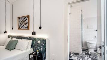A bedroom with a bed, bedside table, and a wall-mounted artwork.