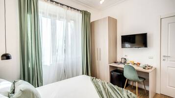 Una habitación de hotel con una cama, un escritorio con una silla, un televisor y un armario.