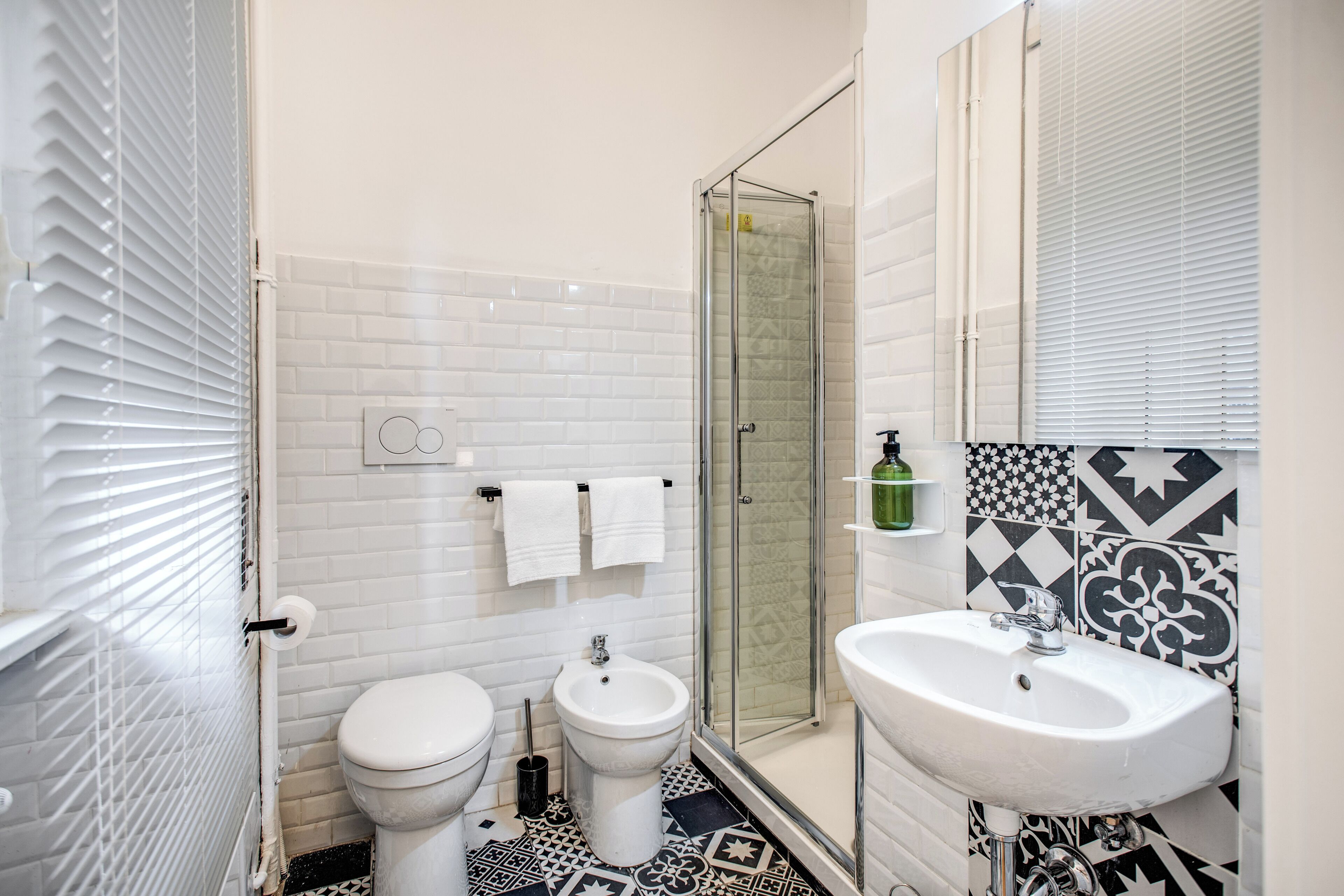 Un baño con inodoro, bidé, cabina de ducha de vidrio y lavamanos.