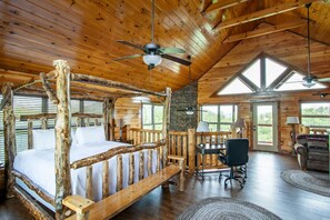 Ein Innenraum einer Blockhütte mit einem hölzernen Bett, einem Schreibtisch und einem Essbereich.