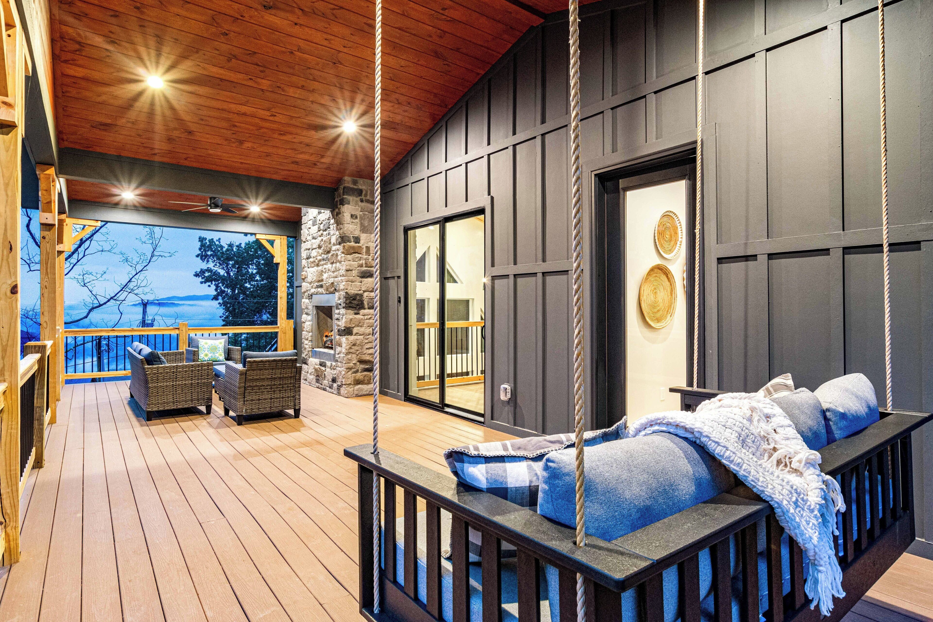 A wooden deck with wicker furniture, a swing, and a stone wall.