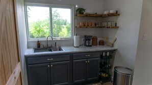 A kitchen with dark cabinets, a window, and a countertop with various items.
