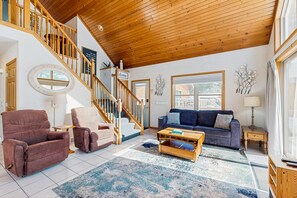 Relax in this inviting living area with a large window offering a view of the outside, a round mirror, and comfortable seating for two.