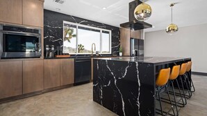 Una cucina moderna con isola in marmo, elettrodomestici in acciaio inossidabile e un angolo bar con sgabelli.