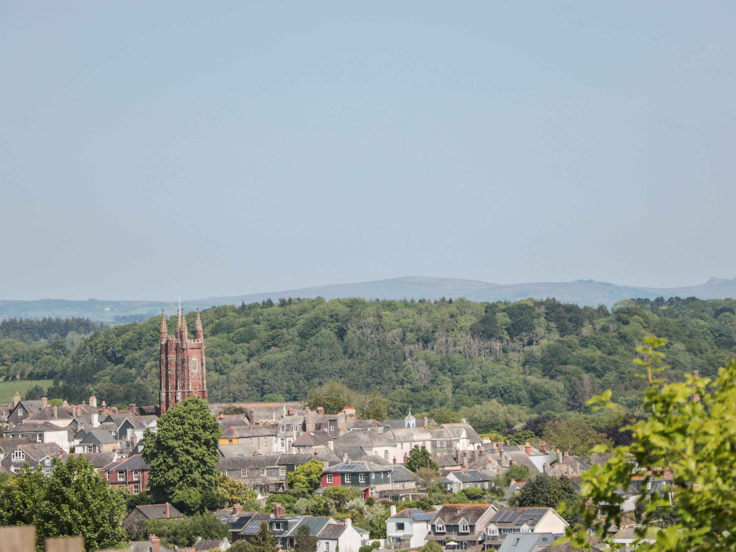 A town with a prominent church tower, surrounded by residential buildings and lush greenery.