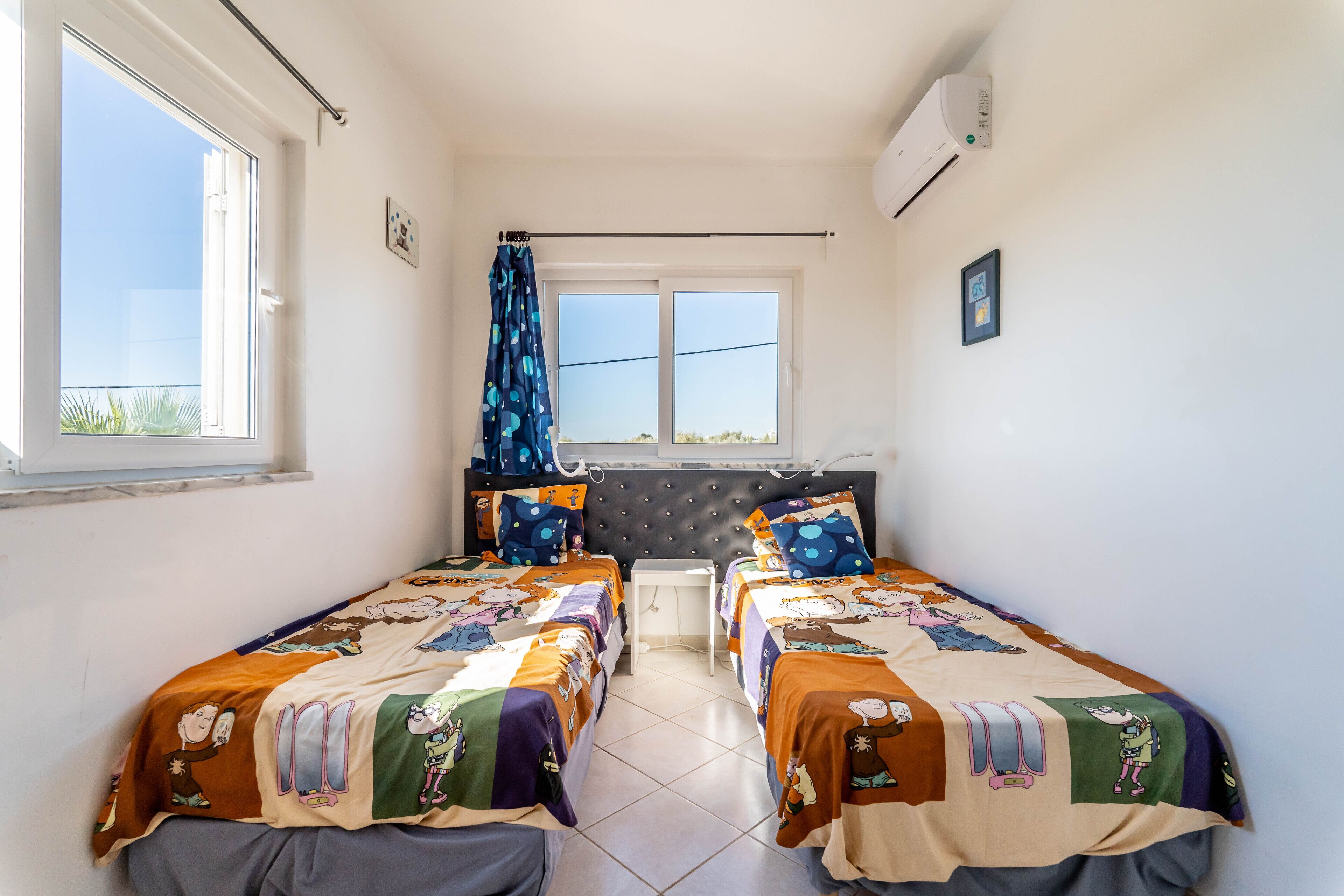 A bedroom with two beds, a window, and an air conditioning unit.