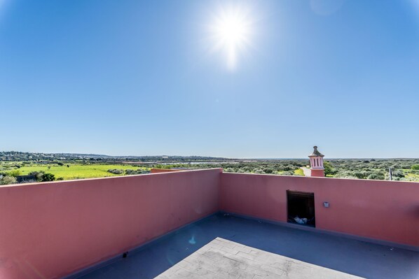 A rooftop terrace with a clear view of a distant landscape, a small tower-like structure, and a door leading to an interior space. - Villa Paradis  (Silves)