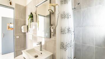 Een moderne badkamer met een wastafel, spiegel en douche.