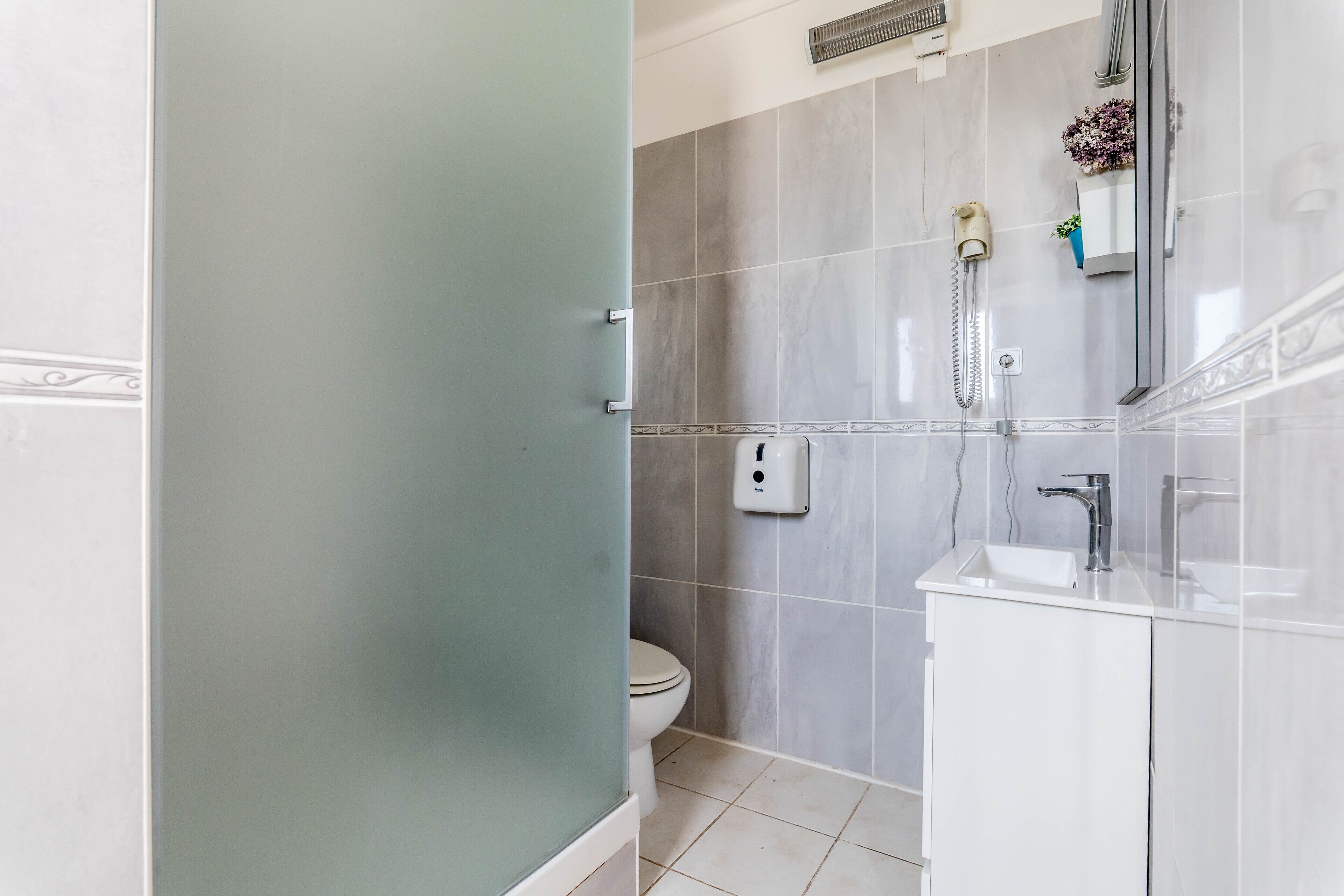 A bathroom with a toilet, a shower, and a sink.