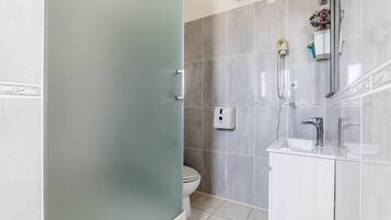A bathroom with a toilet, a shower, and a sink.