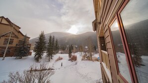 A snowy landscape with a mountain in the background, a wooden building with a window, and a clear sky. - Red Hawk Lodge 2220 (Keystone)