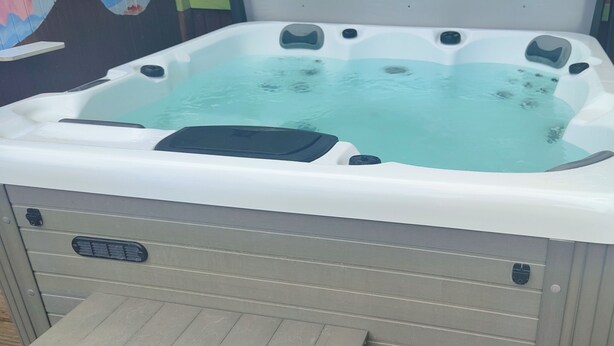 A hot tub with a control panel, a drain, and a wooden deck surrounding it. - The Cabin Quiet, Relaxing and dog Friendly (Mauchline)