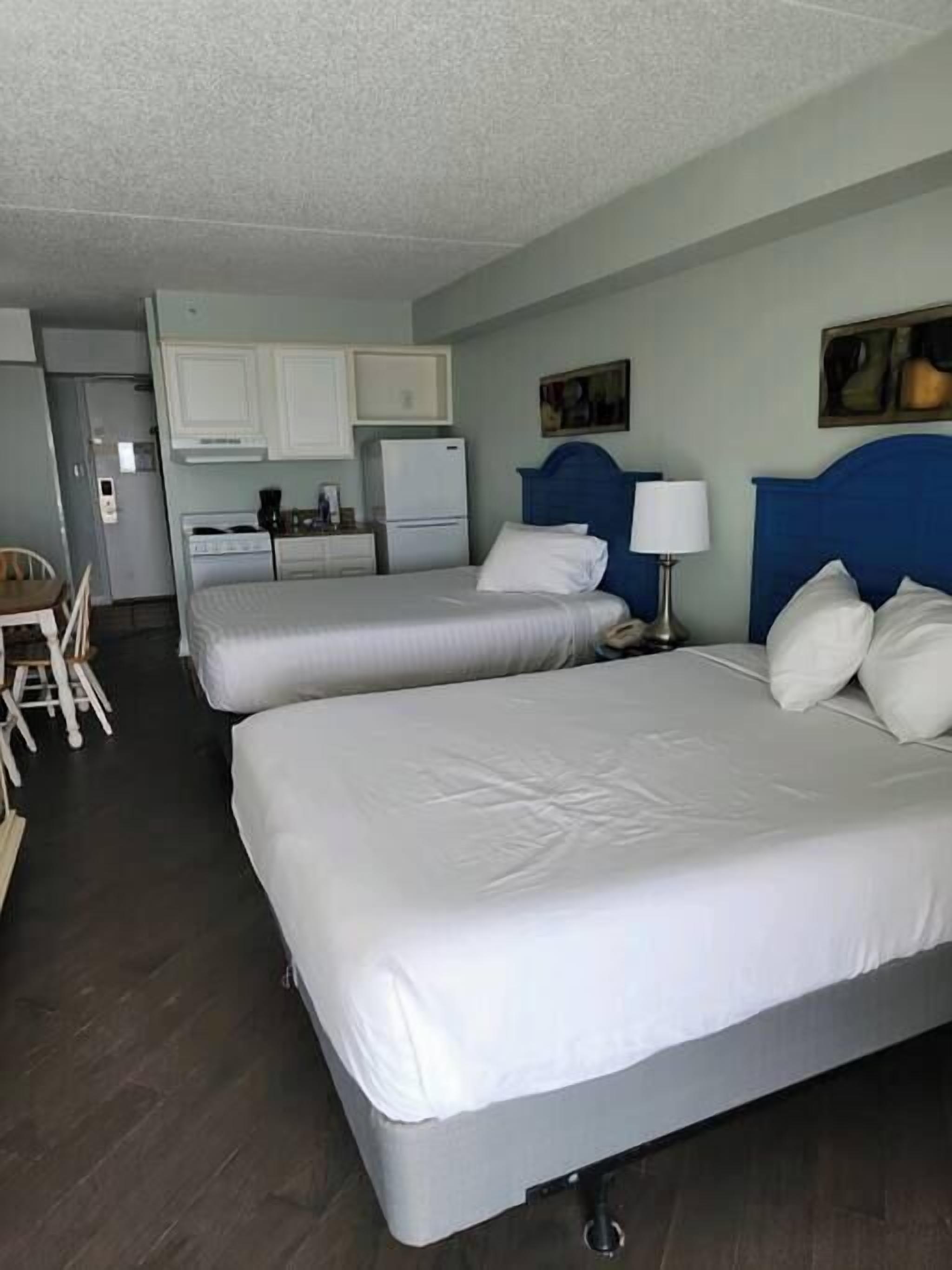 Une chambre d’hôtel avec deux lits, une kitchenette, un coin repas et une petite salle de bain.
