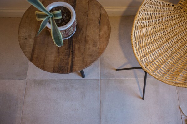 A round wooden table with a potted plant and a wicker chair. - Bosque Divino Cabañas & Suites (El Nihuil)