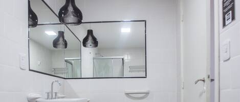 A bathroom with a white sink, toilet, and bidet, a mirror above the sink, and a black and white checkered floor.