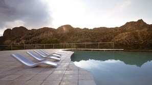 A poolside area with lounge chairs and a view of mountains. - Bosque Divino Cabañas & Suites (El Nihuil)