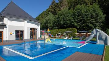 Relax by the clear pool surrounded by a deck and lush greenery.