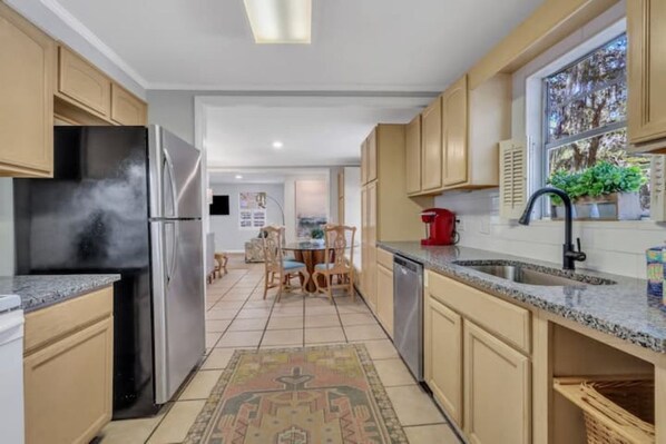 Enjoy meals in the kitchen with a stainless steel refrigerator, dishwasher, and coffee maker, leading to a dining area with a wooden table and chairs.