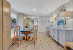 A spacious kitchen with a central island, wooden chairs, and a dining table.