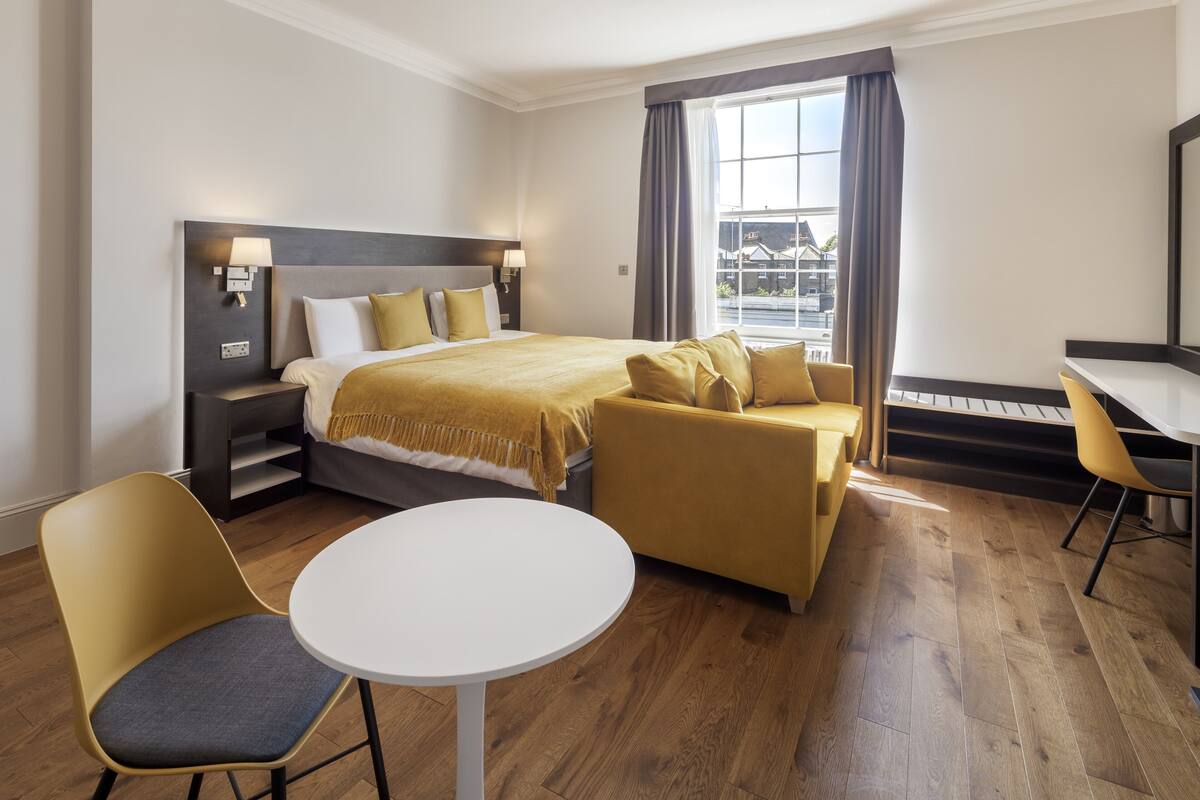 A hotel room with a bed, bedside tables, a desk, and a chair.
