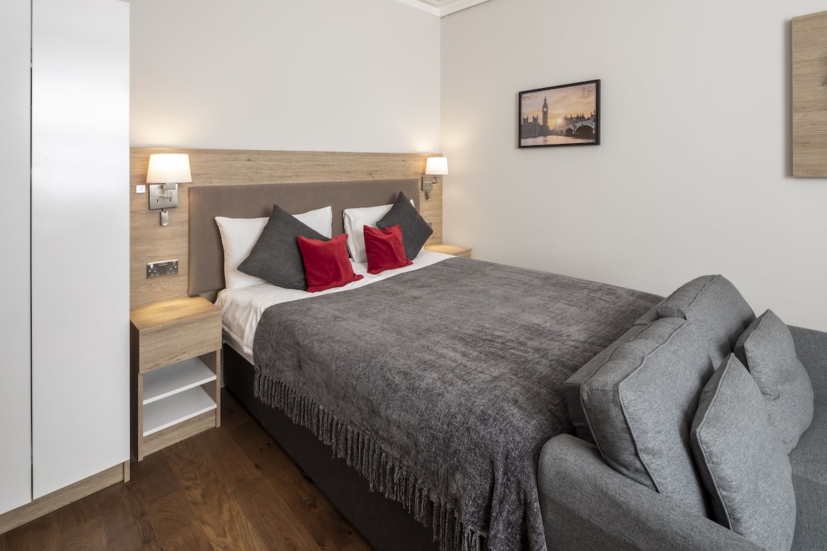 A neatly arranged bedroom with a bed, bedside tables, and a wall-mounted lamp.