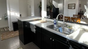 Una cocina moderna con una isla central, pileta de acero inoxidable y muebles negros.