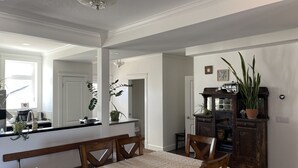 Un comedor con una mesa dispuesta para cuatro, un banco de madera, un espejo y un mueble de madera oscura con plantas.