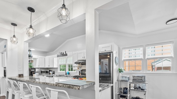 A modern kitchen with white cabinetry, a granite island with bar stools, and pendant lighting. - Ranch Home w/ Backyard Retreat, Near Downtown Atl, Ask Flex Check In/Out! (Atlanta)